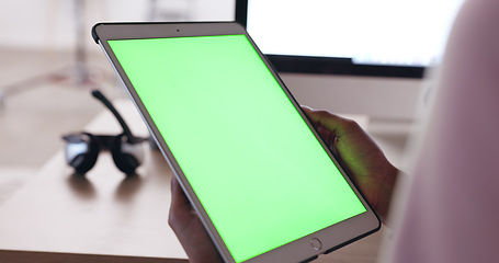 Image showing Close up of an African American persons hands holding a tablet with a plain green screen with a blurred background of headphones. Technician working out how to fix broken device. IT problem solving