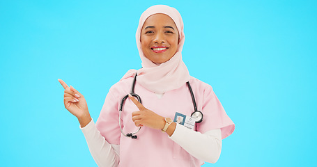 Image showing Woman doctor pointing to mockup isolated on blue background for healthcare presentation or product placement space. Happy face of nurse or medical muslim person show advertising mock up in studio