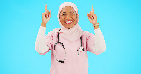 Image showing Muslim nurse, happy woman and pointing finger portrait with space for healthcare, religion or happiness. Islamic female medical worker with hand, smile and hijab for announcement on blue background