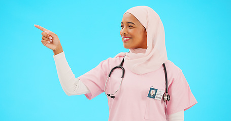 Image showing Face, nurse and Muslim woman pointing to mockup in studio isolated on a blue background. Portrait, healthcare professional and happy Islamic person with marketing, advertising or product placement.