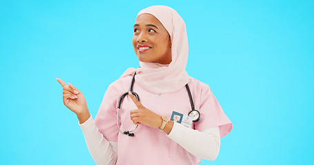 Image showing Woman doctor pointing to mockup isolated on blue background for healthcare presentation or product placement space. Happy face of nurse or medical muslim person show advertising mock up in studio