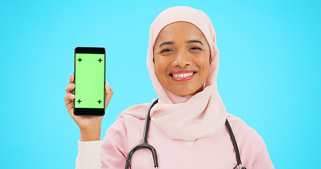 Image showing Green screen, phone and nurse isolated on blue background with medical mobile app, tracking marker and healthcare mockup. Happy islamic doctor or woman face with cellphone product placement in studio