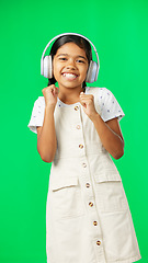 Image showing Children, music and dance with a girl on a green screen background in studio streaming audio. Portrait, smile and fun with an adorable little girl dancing while listening to the radio on headphones