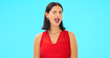 Image showing Happy, woman and winking face on blue background, studio and color backdrop. Portrait, female model and smile for wink, secret and fun mood in red dress, personality and happiness for flirting emoji