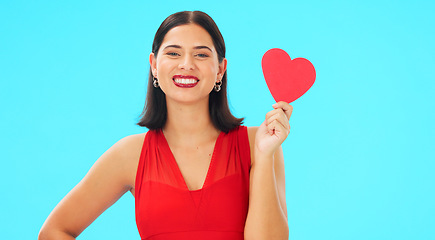 Image showing Paper heart, happy woman and face on blue background, studio and backdrop. Portrait of female model in red dress with shape of love, trust and romance for valentines day, flirting and elegant smile