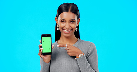 Image showing Woman, pointing and phone green screen mockup with a smile and hand for advertising website space. Face of indian female model with smartphone for branding app, logo or ux while happy and excited