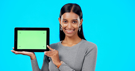 Image showing Mockup, green screen and face of a woman with a tablet isolated on a blue background in a studio. Branding, smile and portrait of an Indian girl holding technology with a blank screen for advertising