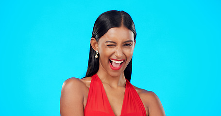 Image showing Wink, happy woman face and studio with isolated blue background and a flirty model. Beauty, young female and smile of a person laughing with confidence in cosmetics and makeup with happiness