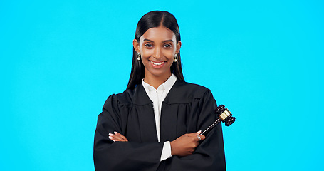 Image showing Lawyer, face and happy woman with gavel in studio, blue background and color backdrop. Portrait, female judge and legal attorney with arms crossed, smile and confidence for justice of constitution