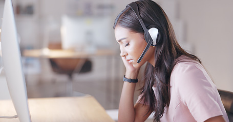 Image showing Young call center agent suffering from a headache or migraine while working in customer service. Support employee feeling tired, overworked and sick while wearing a headset at her desk in the office