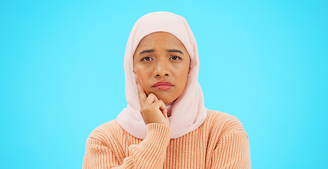 Image showing Muslim woman, thinking and idea with hand on face for mockup, advertising or thought. Serious islamic female with hijab and emoji for doubt, sad and to think about option on a studio blue background