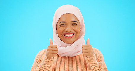 Image showing Muslim woman, happy and thumbs up portrait in studio for mockup, advertising or promotion. Islamic female with hand emoji, smile and hijab excited for announcement or sale on blue background