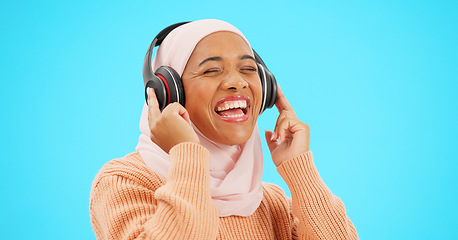 Image showing Happy woman, headphones and dancing isolated on blue background listening to music for celebration and singing . Funny, dance and muslim, gen z or hijab person with streaming technology in studio