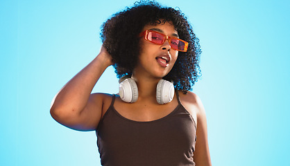 Image showing Face wink, sunglasses and hair care of woman in studio isolated on a blue background. Gen z portrait, retro shades and happy mixed race female model with salon treatment for beauty and headphones.