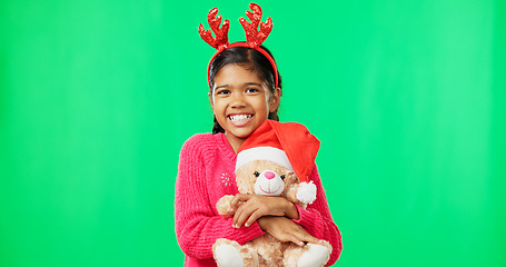 Image showing Happy, Christmas and face of a child with a teddy on a green screen isolated on a studio background. Bear, smile and portrait of a girl kid hugging a toy while excited for the festive season