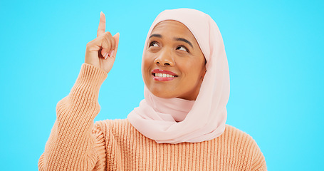 Image showing Happy muslim, woman and pointing finger portrait with space for mockup, advertising or promotion. Islamic female with hand, smile and hijab for announcement, Allah or God and sale on blue background