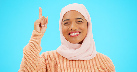 Image showing Happy muslim, woman and pointing finger portrait with space for mockup, advertising or promotion. Islamic female with hand, smile and hijab for announcement, Allah or God and sale on blue background