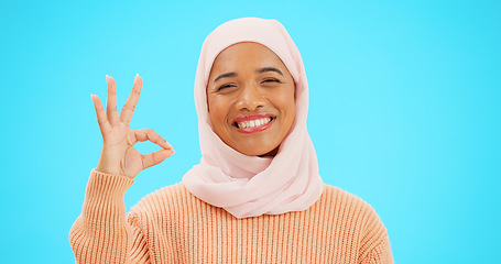 Image showing Muslim woman, ok sign and smile on face with hand for emoji, icon or agreement. Islamic female with hijab and symbol for thank you, support and agreement or approval on a studio blue background