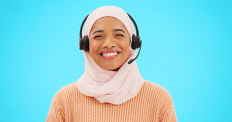 Image showing Call center, woman face and isolated on blue background for agent, consultant or muslim telemarketing support. Happy telecom, technical support or communication of hijab person with headset in studio
