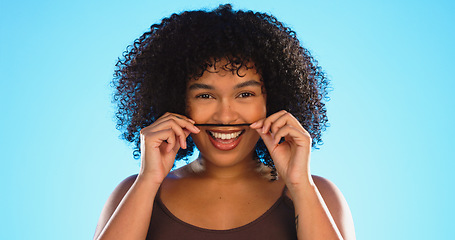 Image showing Hair, moustache and a playful black woman joking in studio on a blue background for fun or games. Portrait, face or haircare and a silly young female comic playing with her hairstyle in comedy
