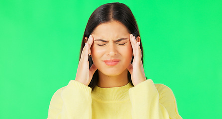 Image showing Stress, frustrated and a woman with a headache on a green screen isolated on a studio background. Burnout, anxiety and a girl massaging her temples to relieve migraine pain on a mockup backdrop