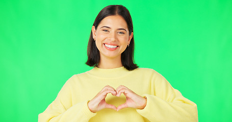 Image showing Heart, hands and face of happy woman on green screen, studio or smile on color backdrop. Female model, portrait and finger shape of love, thank you or support of peace, emoji sign or care of kindness