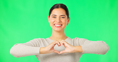 Image showing Heart, hands and face of happy woman on green screen, studio and color backdrop. Portrait of female model, finger shape and love of support, thank you and emoji sign of kindness, care and peace icon