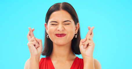 Image showing Happy, woman and face with fingers crossed on blue background, studio and wishing for good luck. Portrait of excited female model hope for winning prize, optimism and smile for emoji, hands and sign