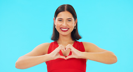 Image showing Face, heart and hands of happy woman on blue background, studio and color backdrop. Portrait, female model and finger shape of love, support and kindness for care, thanks and emoji icon, sign or hope