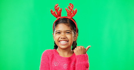 Image showing Christmas, green screen and a girl in a reindeer antlers headband pointing towards chromakey space. Portrait, kids and holidays with an adorable little female child on blank space feeling festive