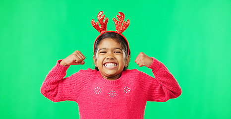 Image showing Child portrait, christmas and antlers on green screen flexing strong muscles or arms for motivation. Smile on face of a girl kid on a studio background with reindeer headband for holiday celebration