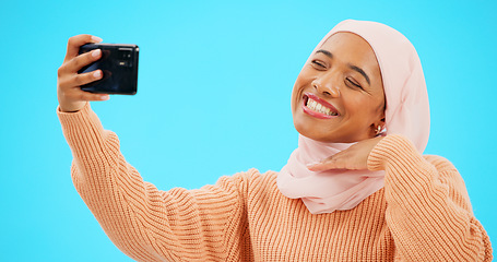 Image showing Selfie of muslim woman isolated on blue background for social media kiss, smile and emoji post online. Face of happy islamic gen z or hijab person in profile picture or influencer lifestyle in studio