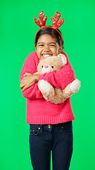 Image showing Christmas, teddy bear and happy with girl in green screen studio for hugging, celebration and festive. Present, cheerful and vacation with child on background for season, holiday and happiness