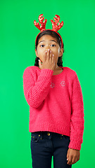 Image showing Child, christmas and shocked on green screen for secret or sale studio background. Face of girl kid with antlers headband and hand on mouth for holiday celebration announcement, surprise or portrait