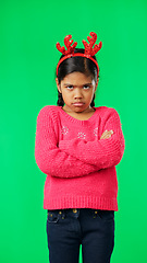 Image showing Portrait, christmas and an unhappy girl on a green screen background standing arms crossed in anger. Kids, sad and frustrated with a miserable little female child looking moody, annoyed or upset