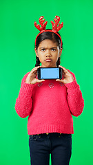 Image showing Christmas face, green screen and kid with phone in studio isolated on a background with tracking markers. Mockup, xmas and sad or unhappy girl with mobile smartphone for marketing or advertising.