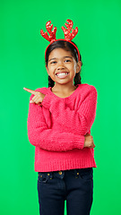 Image showing Child, christmas and pointing at space on green screen with finger or hand. Smile portrait of excited girl kid on studio background with antlers headband for holiday celebration mockup with hands