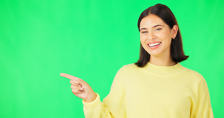 Image showing Portrait, point and space with a woman on a green screen background in studio for marketing or product placement. Hand gesture, advertising and options with an attractive young female on chromakey