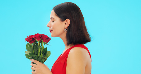 Image showing Rose, smell and face of woman in studio with floral bouquet in celebration of love, romance or valentines day. Portrait, scent and girl happy, smile and excited for flowers against blue background