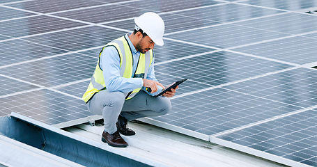 Image showing Young engineer or contractor inspecting solar panels on a roof in the city. One confident young manager or maintenance worker smiling while installing power generation equipment and holding a tablet