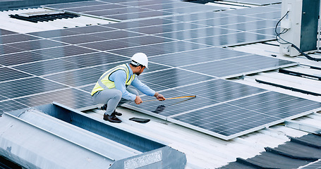 Image showing Engineer or contractor measuring solar panels on a roof of a building. Engineering technician or electrician installing alternative clean energy equipment and holding a tablet to record measurements