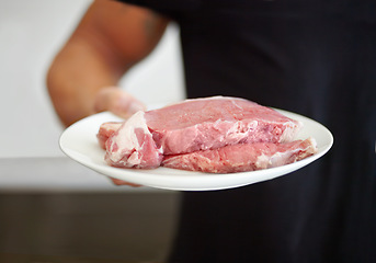 Image showing Food, protein and a plate of raw steak in the hand of a man for diet, nutrition or meal preparation. Kitchen, cooking and meat with a strong male bodybuilder eating beef for a healthy lifestyle