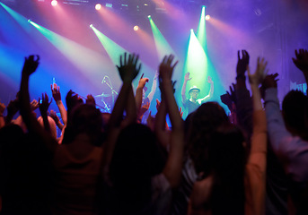 Image showing Fans, people or dancing at concert, music festival or night party, neon lights or event energy. Dance, fun and show, excited crowd in arena and rock band musician in spotlight on stage performance.