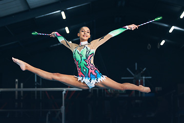 Image showing Performance, gymnastics and female jumping with a ribbon in a professional gym or arena for training. Sports, routine and woman athlete gymnast doing a trick practicing for competition or challenge.