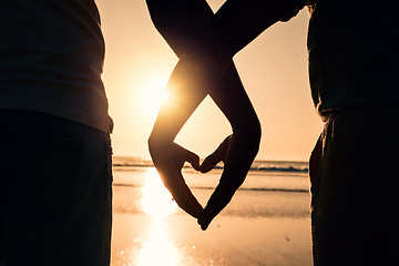 Image showing Sunset, heart hands and couple on the beach while on a vacation, adventure or weekend trip. Romance, silhouette and closeup of man and woman with love gesture in the evening while on romantic holiday