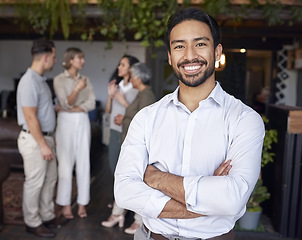 Image showing Portrait, smile and a professional business man in the office, standing arms crossed with his team in the background. Corporate, happy and confident with a young male employee at a work function