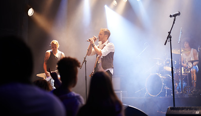 Image showing Music festival, group of people and singer at night for band performance with audience, lights and microphone. Musician or men singing on stage at concert or event, real crowd or young fans listening