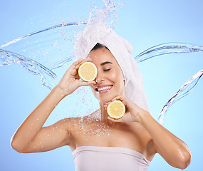 Image showing Shower, lemon and water splash with woman in studio for natural cosmetics, beauty and mockup. Happy, fruits and spa hydration with female on blue background for vitamin c, face and skincare