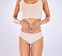 Image showing Heart, body and hands on woman stomach in studio as motivation for weight loss, diet or fitness. Female on a white background with hand emoji for gut health, wellness and skin care in underwear