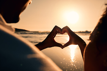 Image showing Sunset, beach and couple with a heart symbol while on a vacation, adventure or weekend trip. Romance, silhouette and closeup of man and woman with love hand gesture in the evening on romantic holiday